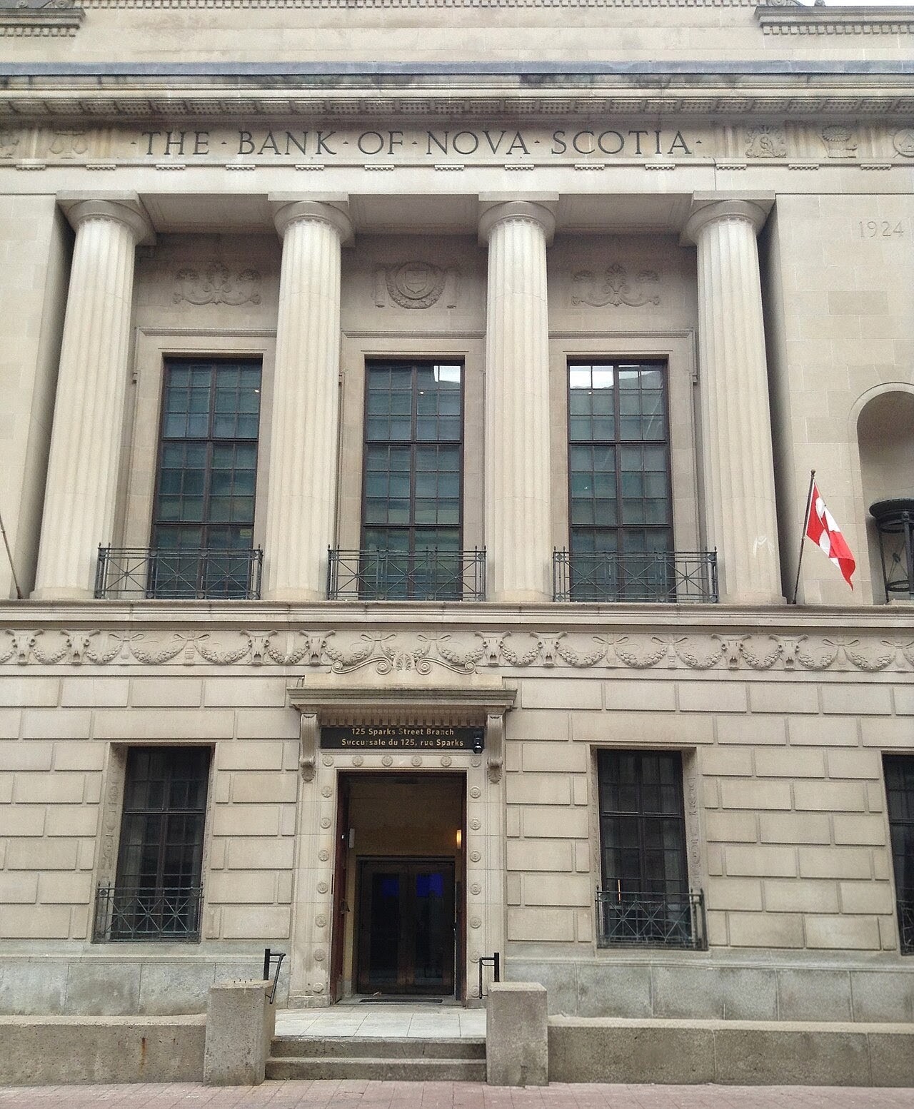 The Beaux-Arts sandstone facade of the former Bank of Nova Scotia at 125 Sparks Street: four fluted Doric columns beneath the carved name and the date 1924, above a modest street-level entrance.